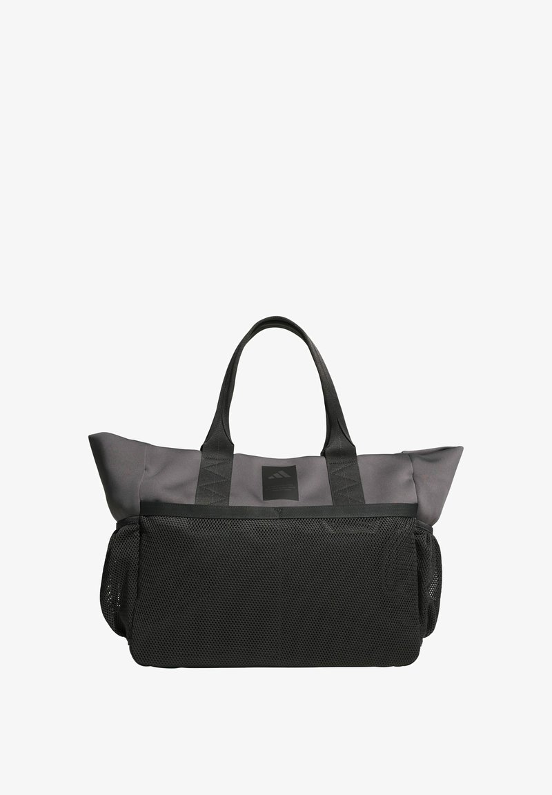 Šedá taška z mrežoviny s čiernymi doplnkami, vybavená dvoma pevnými rukoväťami, obdĺžnikovým tvarom a pevnou nášivkou s logom na prednej strane.