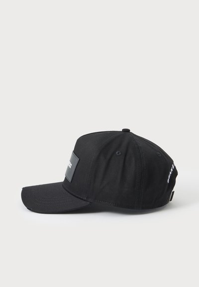 Casquette de baseball noire avec une visière incurvée et un patch rectangulaire sur le devant, vue de profil sur un fond clair uni.