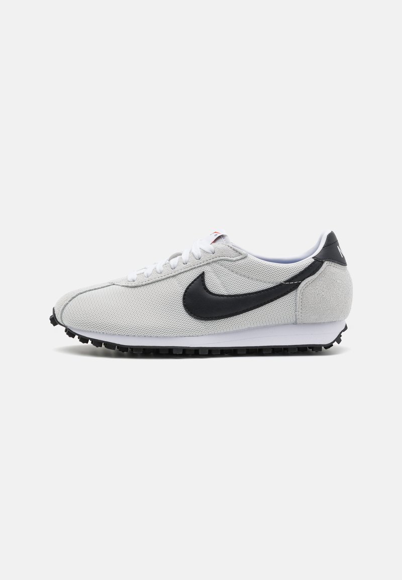 Sivi tenisice s crnim akcentima, teksturiranom gornjom površinom, bijelim vezicama i bijelim međuslojem. Imaju crni Swoosh logo i teksturiran potplat.