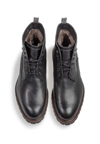 Botas de tobillo de cuero negro con un acabado texturizado, punta redonda y diseño con cordones. Presenta un suave forro de piel y suela de goma marrón.