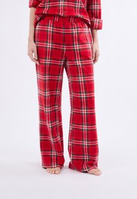 Set di pigiama a quadri rossi realizzato in morbido tessuto. I pantaloni hanno una vestibilità comoda, una vita elastica e un classico motivo tartan con accenti neri e bianchi.