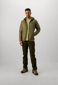 Alyvuogių žalios spalvos pūkinė striukė su gaubtu, derinama su šviesiai žalios spalvos marškinėliais ir tamsiai žaliomis kelnėmis. Paprastas dizainas be matomų raštų.