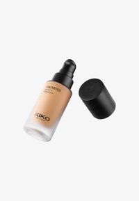 Bottiglia di vetro trasparente con finitura opaca, contenente fondotinta liquido di colore beige chiaro. Dispenser a pompa nera e tappo, etichettata "Fondotinta Opaco Unlimited 24H".