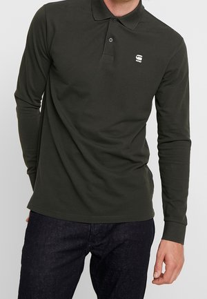 Mørkegrøn langærmet polo-shirt lavet af bomuld. Har en klassisk krave og et lille hvidt logo på brystet. Slim fit design.
