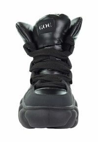 Czarne sneakersy za kostkę z błyszczącym wykończeniem, z charakterystycznymi, wypchanymi akcentami przypominającymi uszy oraz grubymi czarnymi sznurówkami. Okrągła podeszwa dla lepszej amortyzacji.