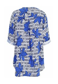 Bluse mit kurzen Ärmeln in blauer Blumenoptik und weißem Text, oversized geschnitten und locker fallend. Auffällige Muster umfassen große Blumen und kräftige Schriftzüge.
