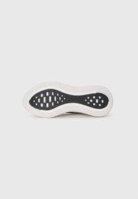 Shoe sole features a black textured surface with a honeycomb pattern and white rubber edge, curved shape for improved grip and support.