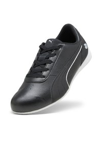 Chaussure de sport noire avec une tige en cuir lisse, un design à lacets, des détails perforés, des accents blancs et une semelle en caoutchouc.