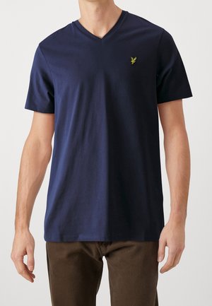 Marineblå bomulds t-shirt med korte ærmer, v-hals design, der har et lille grønt emblem på brystet og en glat, ensartet tekstur.