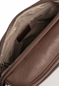 Borsa in pelle marrone con cerniera aperta che rivela l'interno in tessuto beige con nome del marchio stampato e una tasca interna con cerniera.