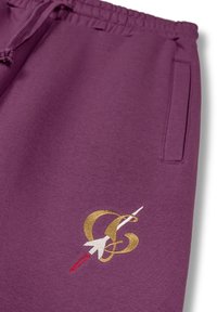 Pantalones deportivos morados hechos de una tela suave, con un diseño dorado bordado que incluye una flecha blanca y acentos rojos. Incluye un bolsillo lateral.