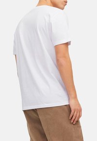 White cotton t-shirt with short sleeves and a relaxed fit, features a classic crew neckline. Smooth texture; no visible patterns or logos.