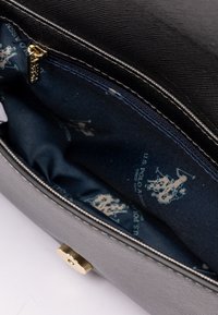 Szara torebka kopertowa z fakturą i złotymi akcentami; wnętrze ma niebieską podszewkę z powtarzającym się wzorem logo U.S. Polo Assn. Widoczny zamek błyskawiczny.