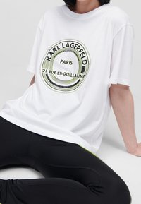 Witte katoenen t-shirt met een grafisch ontwerp met zwarte en neon groene tekst, "Karl Lagerfeld Paris 21 Rue St-Guillaume." Relaxte pasvorm.