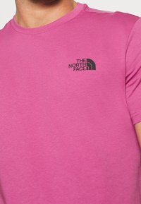 Tričko s krátkým rukávem, kulatým výstřihem v jasně růžové barvě z bavlny s černým logem The North Face na levém hrudníku. Měkká textura, volný střih.