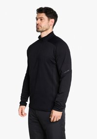 Schwarzes, sportliches Langarmoberteil mit hohem Kragen und Viertelreißverschluss. Verfügt über einen strukturierten Stoff und ein Logodetail am linken Ärmel.