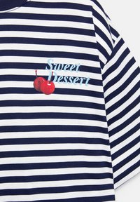 Blå og hvid stribet t-shirt med korte ærmer, der har teksten "Sød Dessert" trykt på brystet samt to røde kirsebær.