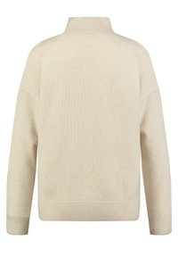 Maglione beige, lavorato a maglia, con collo alto, vestibilità ampia, spalle scese e polsini a coste. La texture è morbida e liscia.