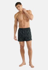 Černé plavky s květinovým vzorem, s knoflíkem a kontrastním pasem. Vyrobené z lehké látky pro pohodlí.