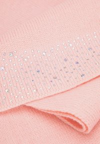 Tissu tricoté rose à texture lisse, présentant des rangées de strass irisés le long du bord, créant un motif décoratif.