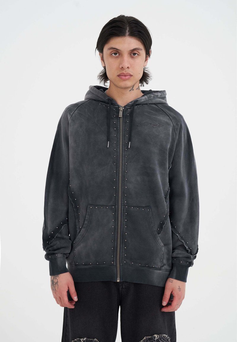 Sudadera con capucha de ante gris y cierre de cremallera, con acentos de tachuelas, bolsillos frontales y capucha con cordón. Presenta un corte relajado y mangas largas.