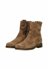 Bottes de cheville en daim marron avec fermeture éclair sur le côté, tirette, talon bas et bouts ronds sur fond blanc.