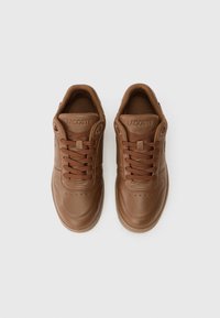 Brązowe skórzane sneakersy z sznurówkami, posiadające teksturowane wykończenie, perforacje na przedniej części buta oraz oznakowane język.