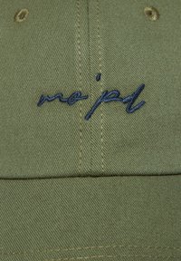 Olijfgroene katoenen pet met gestructureerde stof; heeft marineblauwe geborduurde tekst "me jad" aan de voorkant. Zichtbare stikdetails.