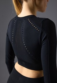 Schwarz langärmliges Sportoberteil mit strukturiertem Strickdesign und offenen Lochmustern entlang des Rückens und der Schultern. Enganliegende Silhouette.