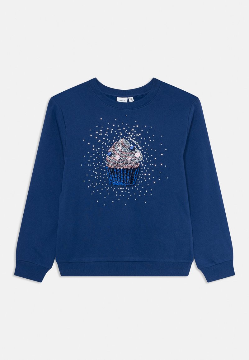 Tums zilas krāsas kokvilnas džemperis ar cupcake grafiku, kas rotāta ar spīdumiem un krāsainiem akcentiem, apaļu kaklu un garām piedurknēm.