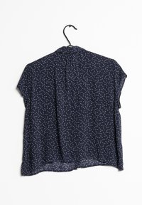 Blusa a maniche corte di colore blu navy con colletto, caratterizzata da un motivo geometrico bianco, tessuto leggero e vestibilità comoda.