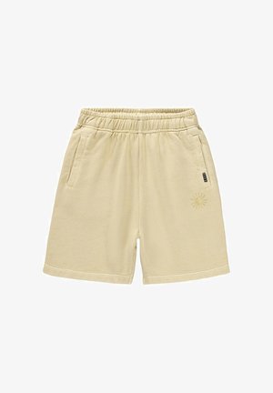 Shorts de algodón beige con cintura elástica, bolsillos laterales y un detalle gráfico de sol en la pierna izquierda. Textura suave y diseño sencillo.