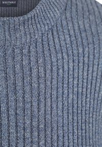 Blauwe ribgebreide trui met een hoge hals en een textuurpatroon, gemaakt van zacht materiaal. Heeft een eenvoudig ontwerp zonder extra accenten.