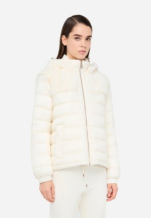 Giubbotto imbottito di colore bianco sporco con texture trapuntata, colletto alto, zip frontale e dettagli in pelliccia sulle spalle. Presenta due tasche laterali.
