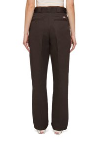 Bruna, högmidjade byxor med rak ben-design, två bakfickor och en logotypöppning nära midjan. Tillverkade av bomull eller bomullsblandat tyg.