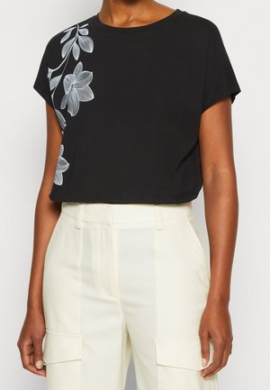 T-shirt noir à manches courtes avec un motif de broderie florale grise sur le côté gauche. Conçu en tissu doux avec une coupe décontractée.
