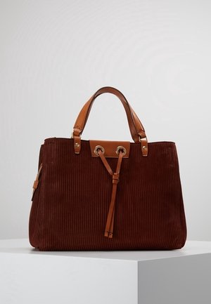 Bolso marrón de pana con asas de cuero color tostado y detalle de cordón, colocado sobre un pedestal blanco contra un fondo claro y liso.