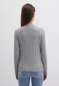 Grauer kabelgestrickter Pullover mit Rundhalsausschnitt und geripptem Saum, der über ein Rippmuster entlang des Rückens und eng anliegende Ärmel verfügt.