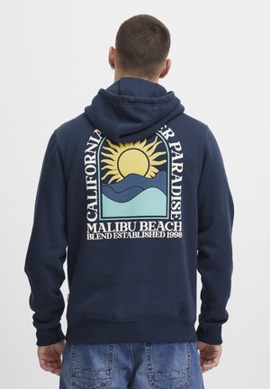 Sudadera azul navy con un gráfico de un sol y olas en la parte posterior. Tejido suave con capucha ajustable y puños acanalados.