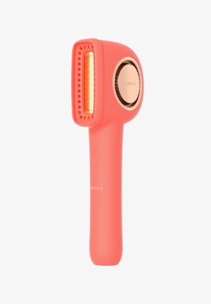 Coral handheld device with a rectangular head, gold accents, textured grip, and a perforated design near the head for light application.