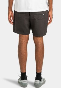 Donkergrijze denimshorts met een relaxte pasvorm, voorzien van twee achterzakken en een gestikte zoom, gedragen met grijs-witte sneakers.