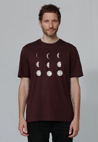 T-shirt bordeaux à manches courtes avec un graphique des phases lunaires en gris clair, mettant en avant des designs de croissant de lune et de lune pleine.