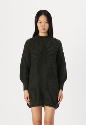 Abito maglione lavorato a maglia spessa di colore verde scuro. Presenta una texture a coste, collo alto e maniche a palloncino. Leggermente più lungo sul retro.