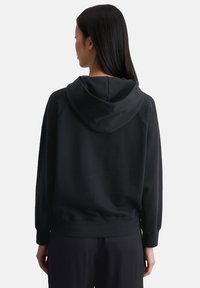 Czarna bluza z kapturem, wykonana z miękkiego materiału, z dużym kapturem z tyłu, rękawami raglanowymi i ściągaczami, bez widocznych wzorów czy logo.