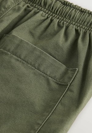 Oliivrohelised püksid elastse vöökoha ja küljetaskuga. Valmistatud vastupidavast kangast, millel on sile tekstuur ja lamedad õmblused.