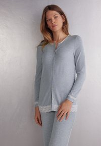 Lichtblauwe pyjama set met lange mouwen, versierd met kant aan de zoom en manchetten, met een ronde halslijn en een sluiting met knopen aan de voorkant. Zacht, lichtgewicht stof.