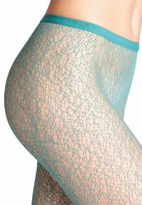 Calze in pizzo color teal con un motivo a nido d'ape, caratterizzate da una vita larga. Il tessuto è semitrasparente con una finitura strutturata.