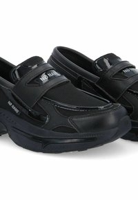Chaussures noires à enfiler avec un dessus en maille, des accents brillants, un col rembourré et une sangle auto-agrippante pour un maintien sécurisé. Semelle extérieure texturée.
