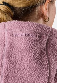 Fleece jack in lichtroze met een gestructureerd oppervlak. Beschikt over gestikte naden en het merk "SWEDEMOUNT" is op de kraag geperst.
