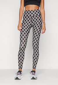 Legíny s černo-bílým vzorem mají geometrický design s hexagonálními tvary, vysoký pas a hladkou, pružnou texturu.